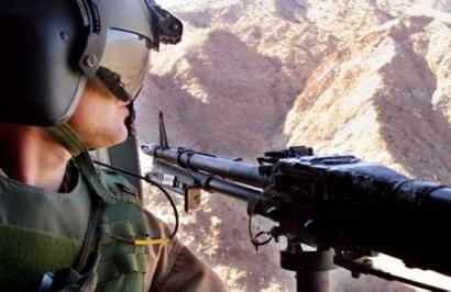 A CH-47D Chinook door gunner looks out from his Chinook helicopter over the mountains of Khost Province in southeast Afghanistan.